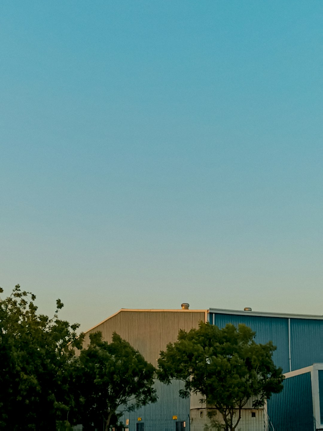 Lone worker silhouette facing factory at dusk