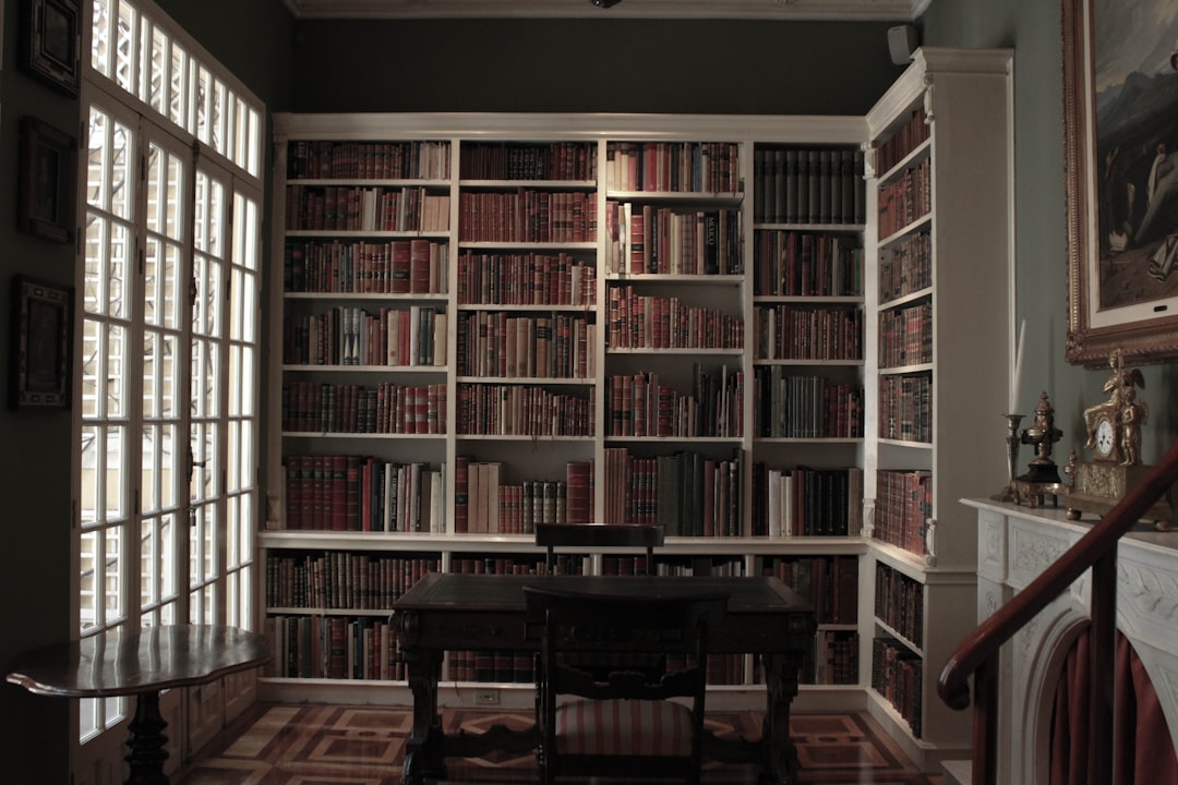 Full dark academia home office with mahogany bookshelves, green walls, and amber lighting