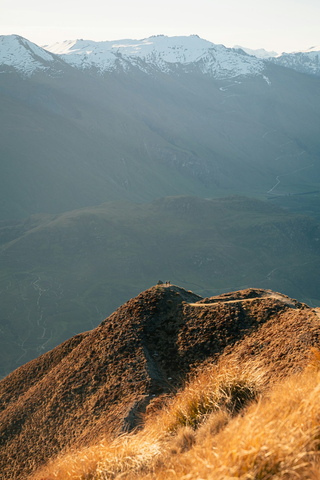 Hiker on mountain ridge using GPS device at golden hour