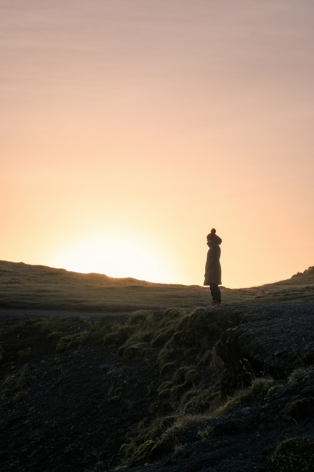 夕暮れの丘で太陽光を浴びる人物のシルエット