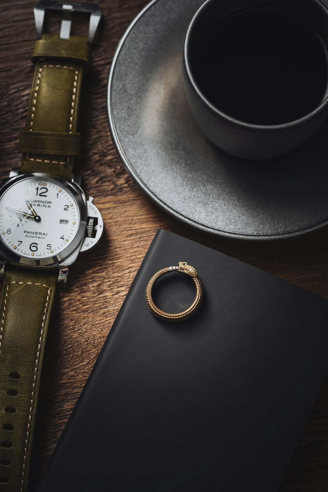 Smart ring beside glowing alarm clock on wooden surface