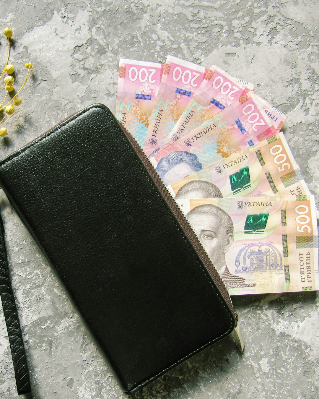 Dompet kulit terbuka di atas permukaan marmer dengan uang di dalamnya