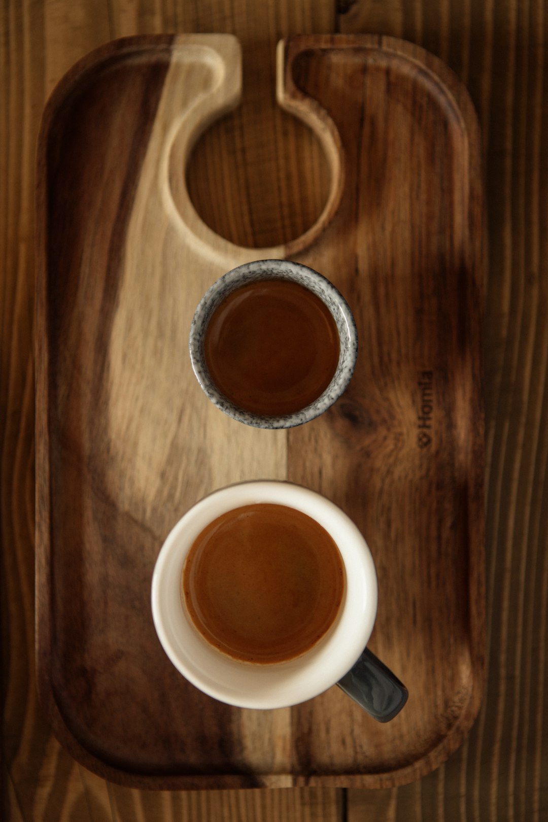 Pour-over coffee brewing into glass carafe on wooden tray