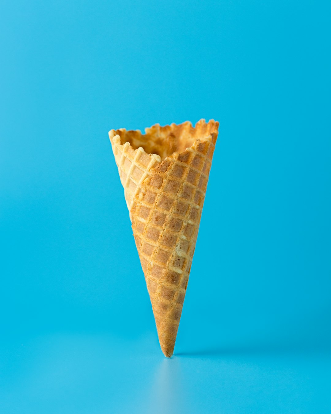 Single ice cream cone held against blue summer sky