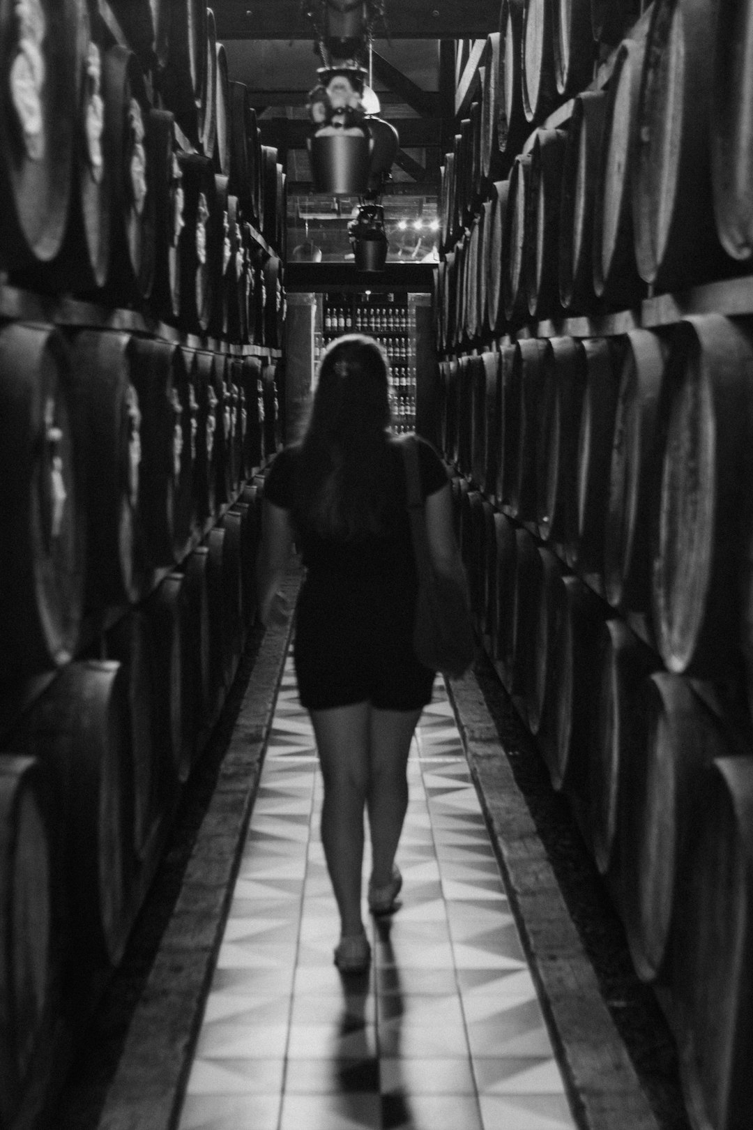 Silhouetted worker walking between whisky barrels