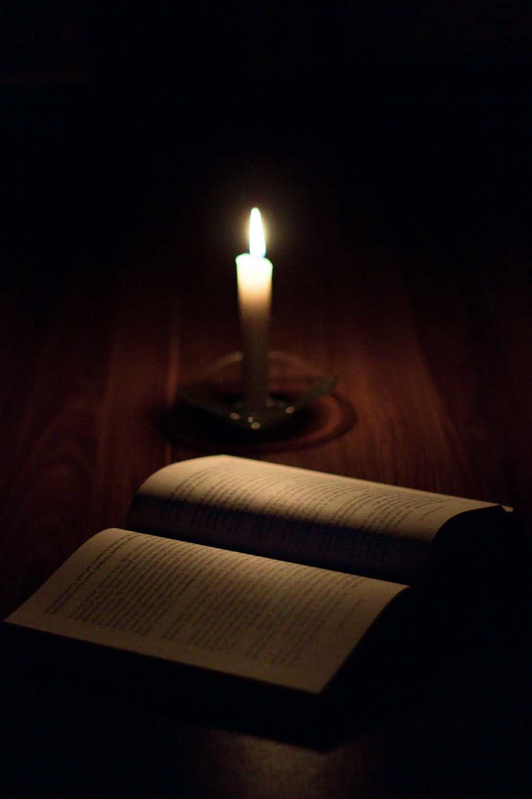Livro aberto com páginas manuscritas e impressas à luz de vela