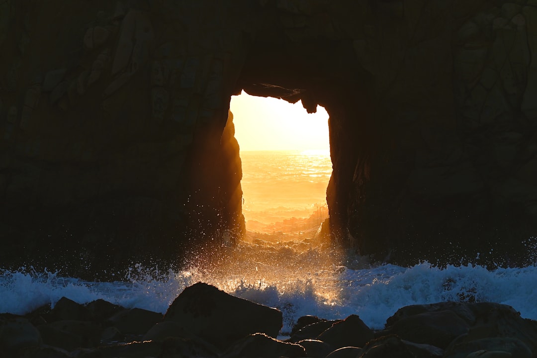 Coastal sea arch with waves crashing through opening