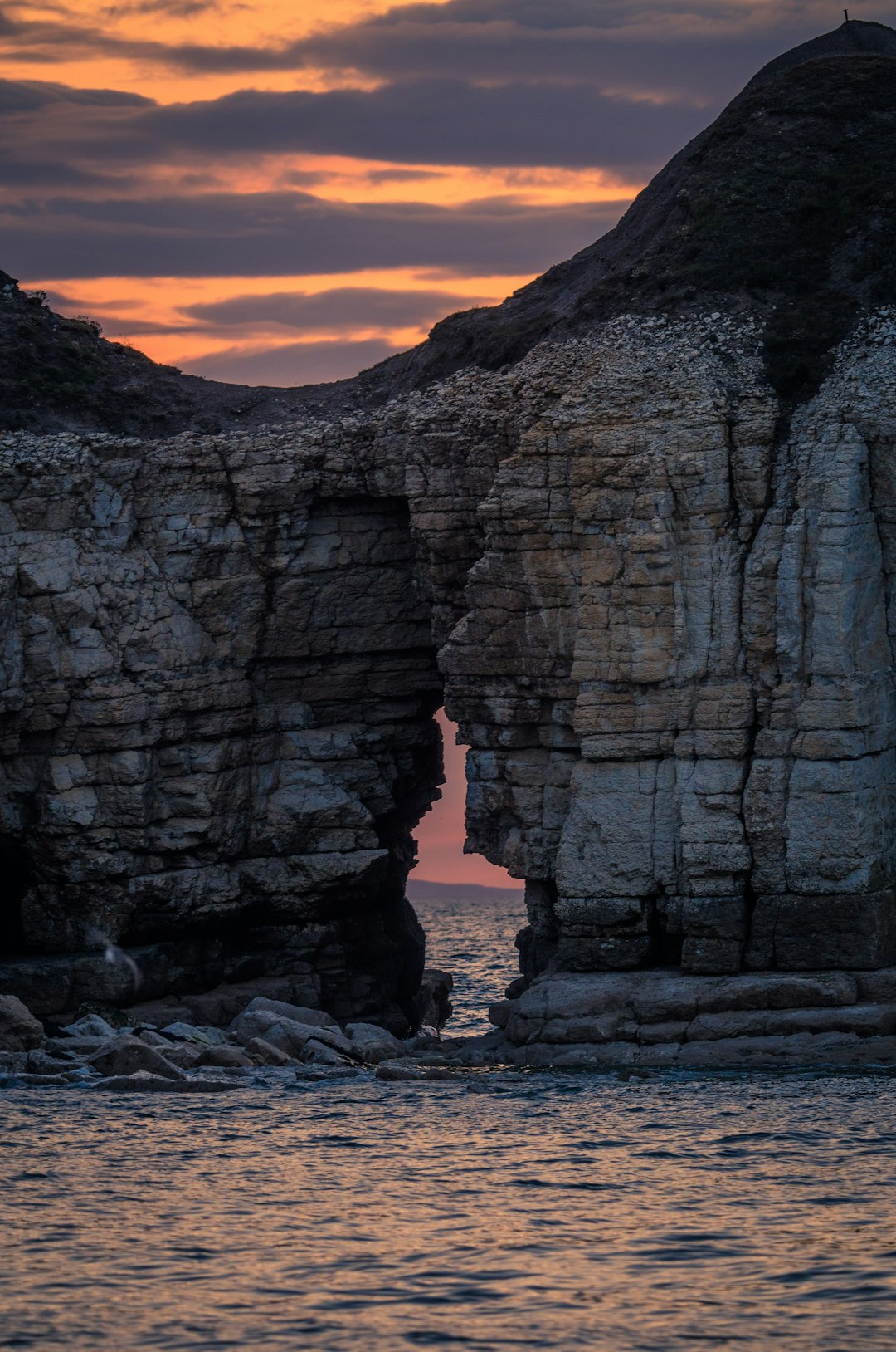 Sea arch silhouette against colorful sunset sky
