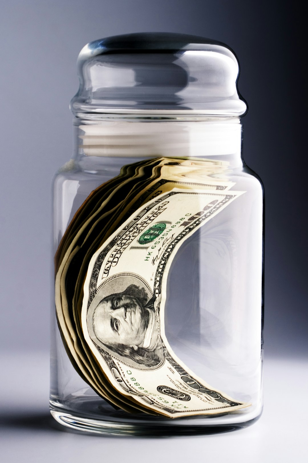Glass jar with savings notes on sunny windowsill