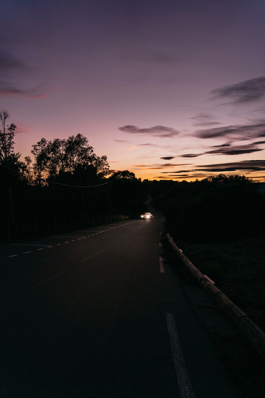 Car silhouette on empty highway at golden hour