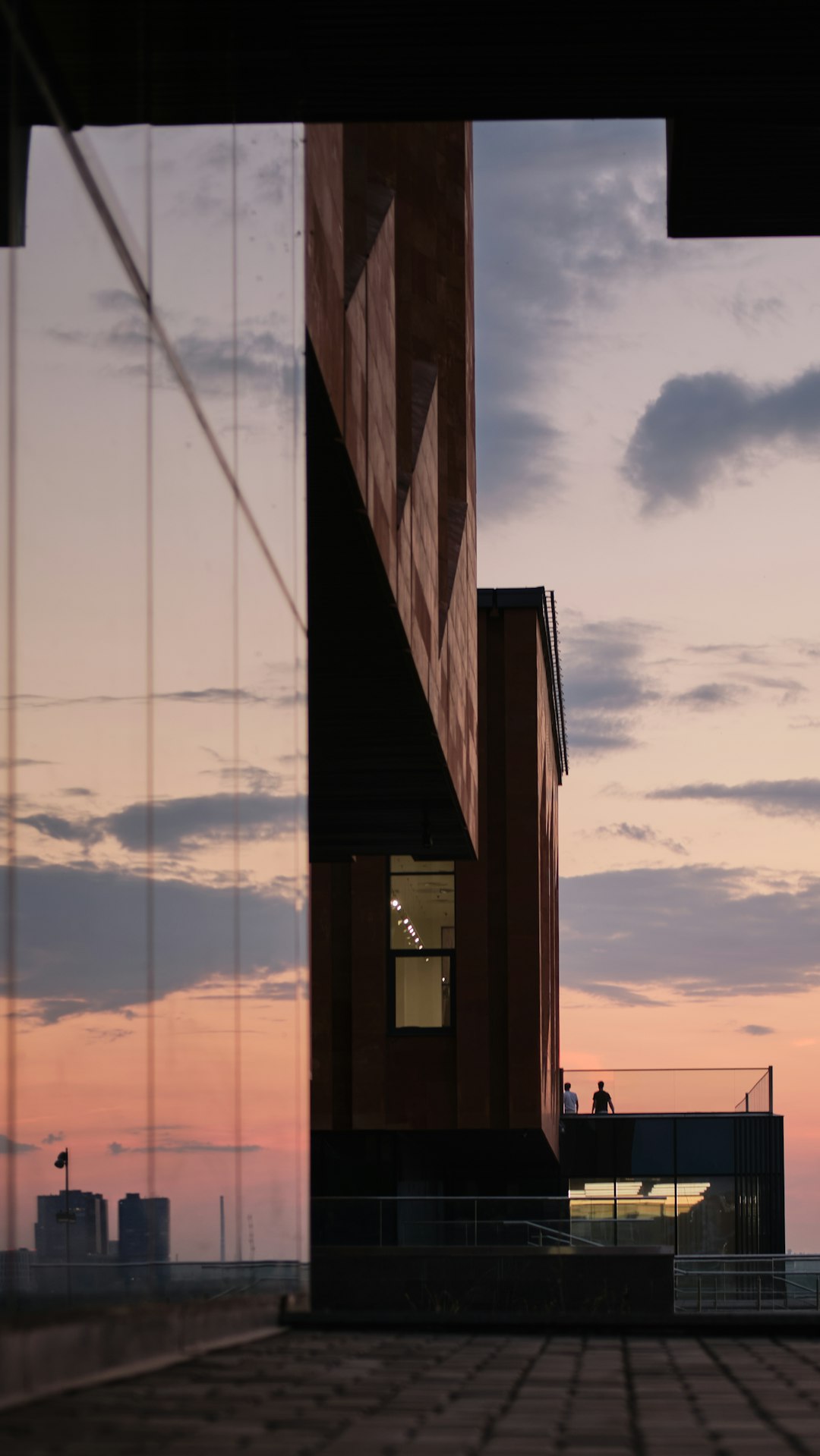 Person steht allein auf Balkon bei Sonnenuntergang über der Stadt