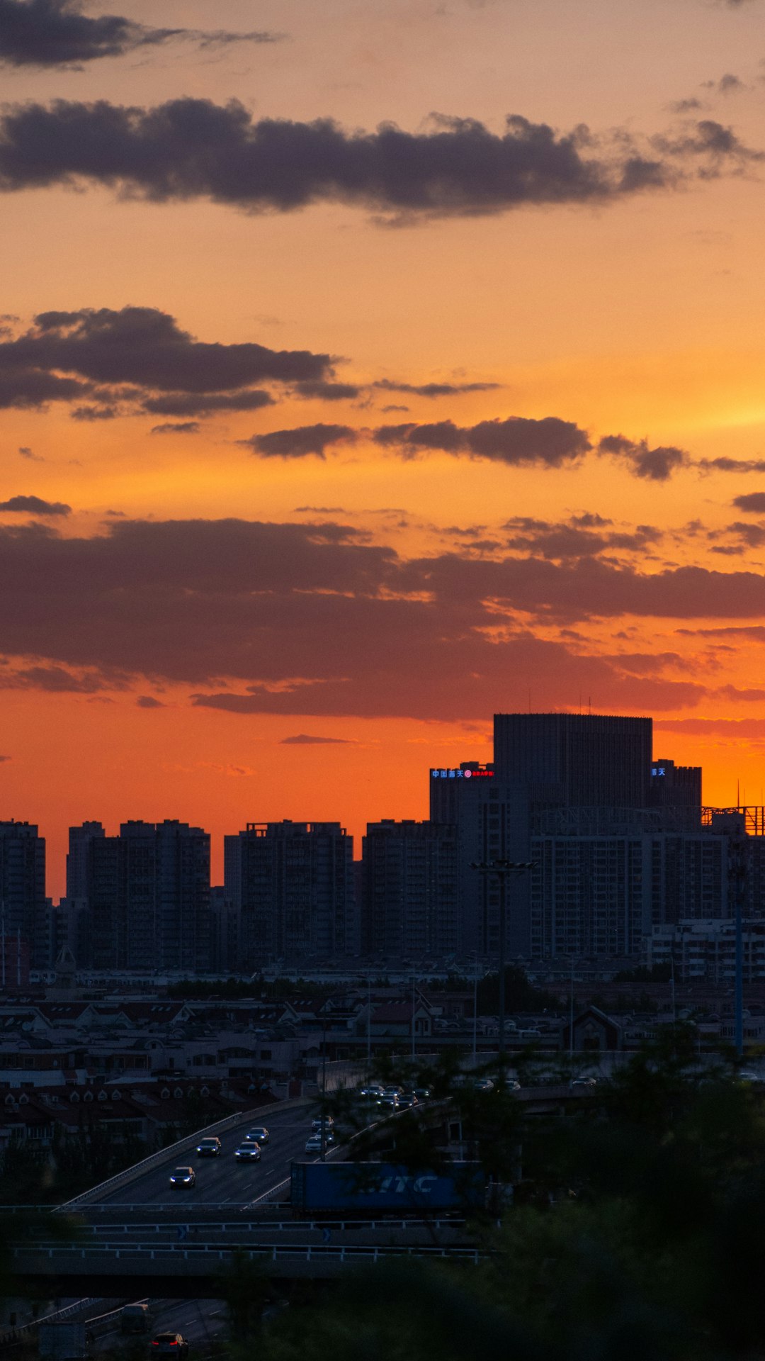 Drone em silhueta contra pôr do sol vibrante sobre cidade