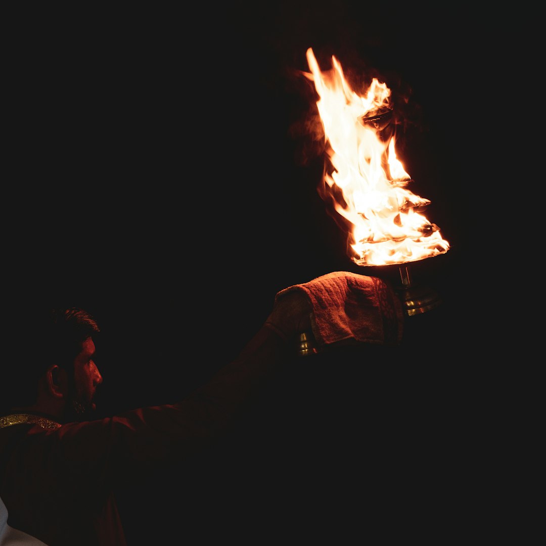 Human hand holding burning torch against dark background