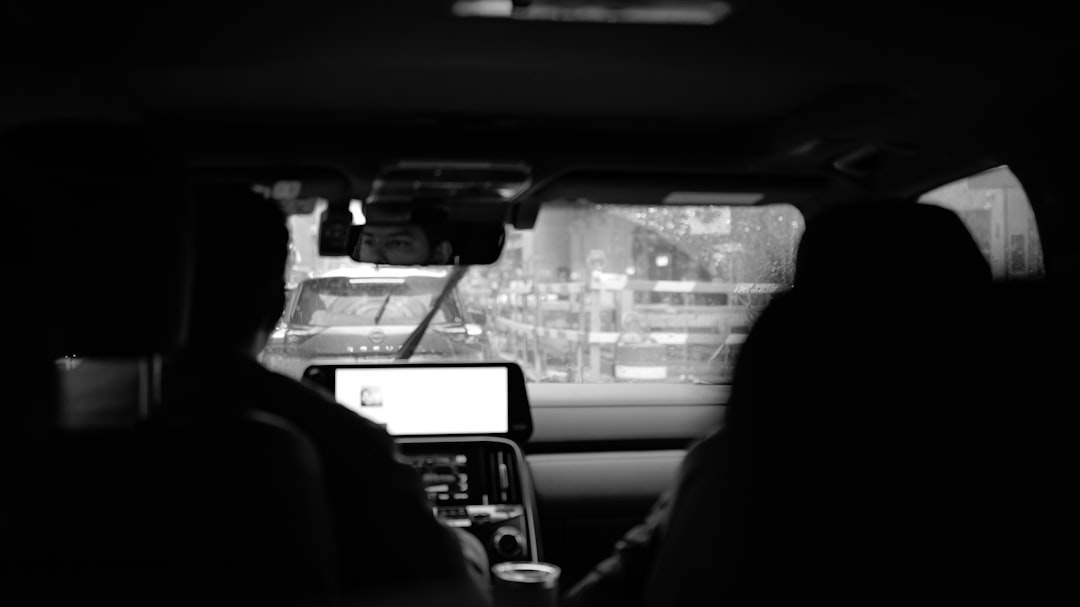 Seseorang memegang HP di dalam mobil yang sedang melaju