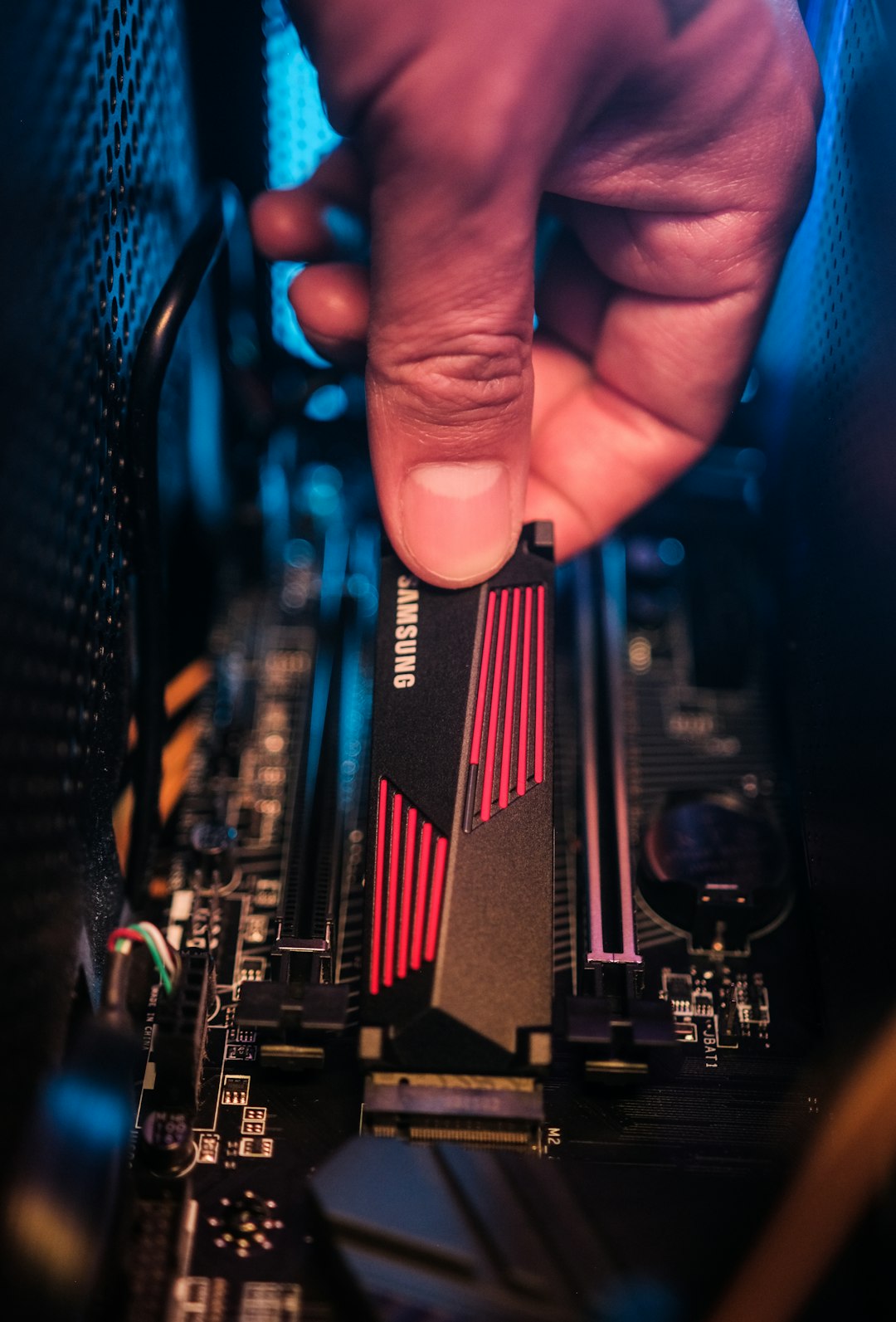 SSD NVMe M.2 dipegang dengan pencahayaan dramatis