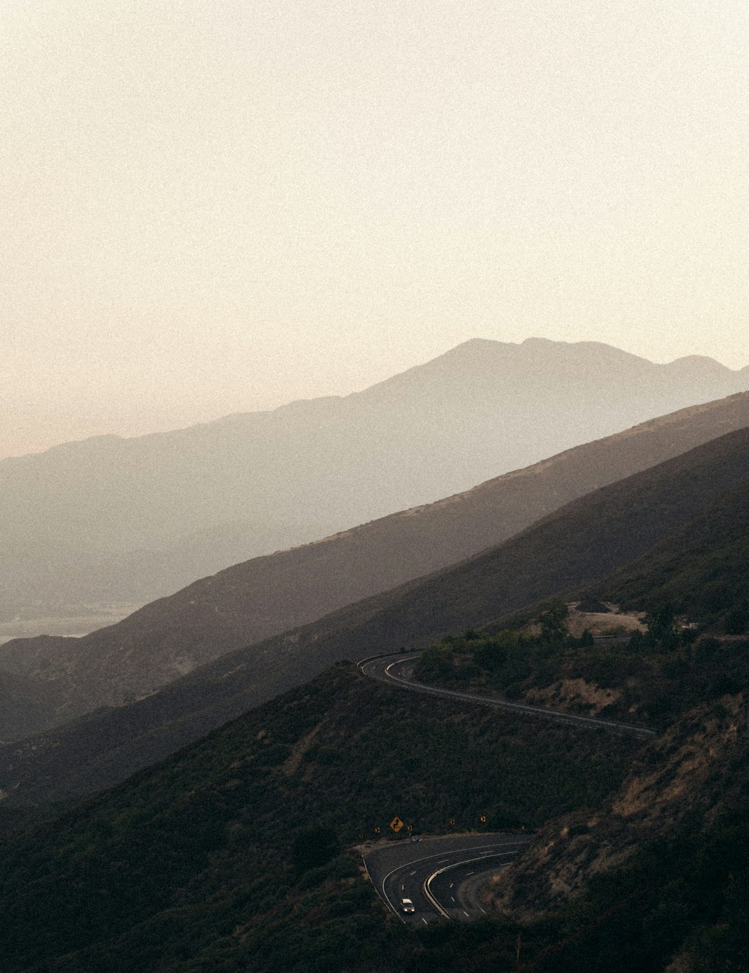 Single car driving on open highway at dusk