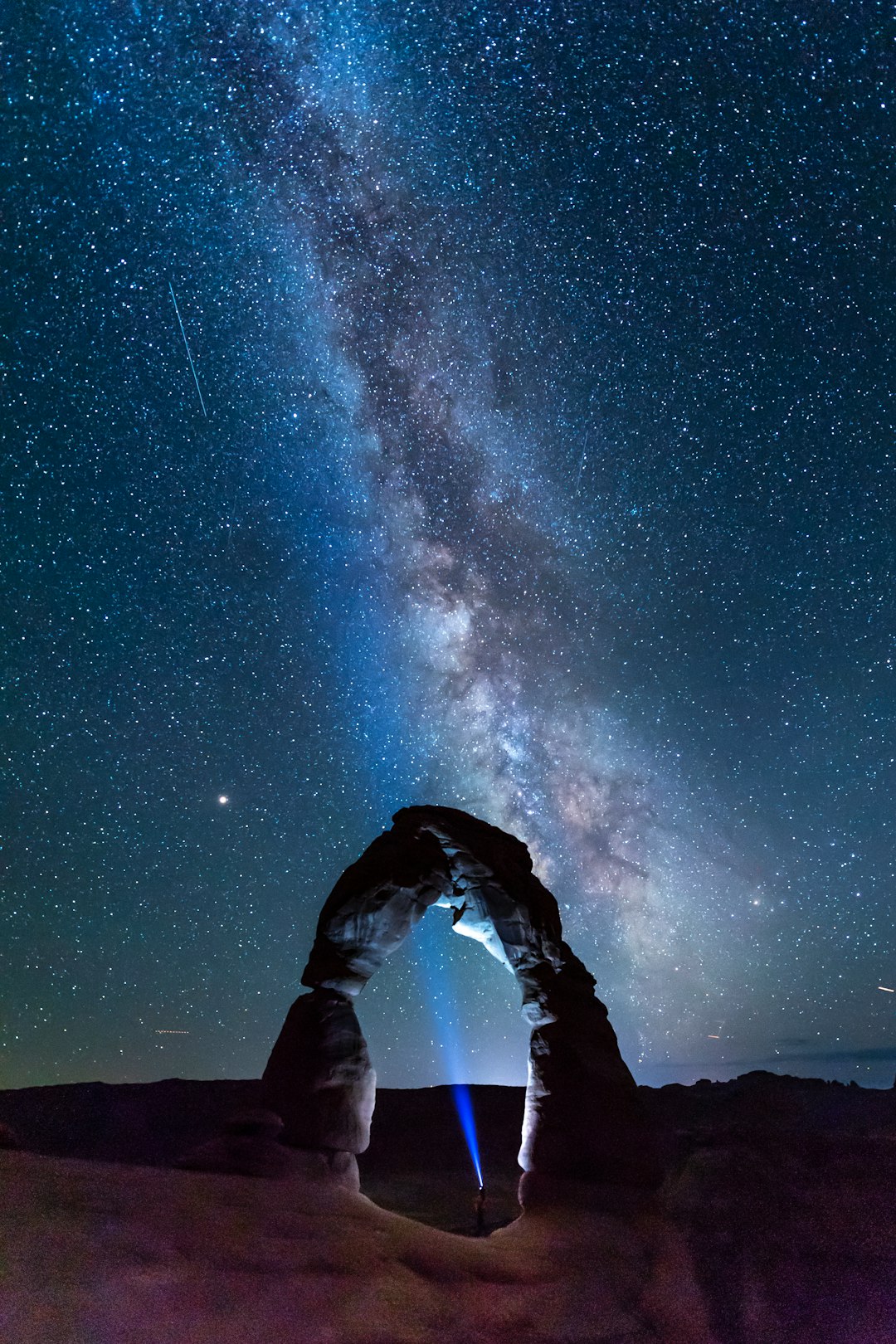 Person silhouetted under the Milky Way night sky