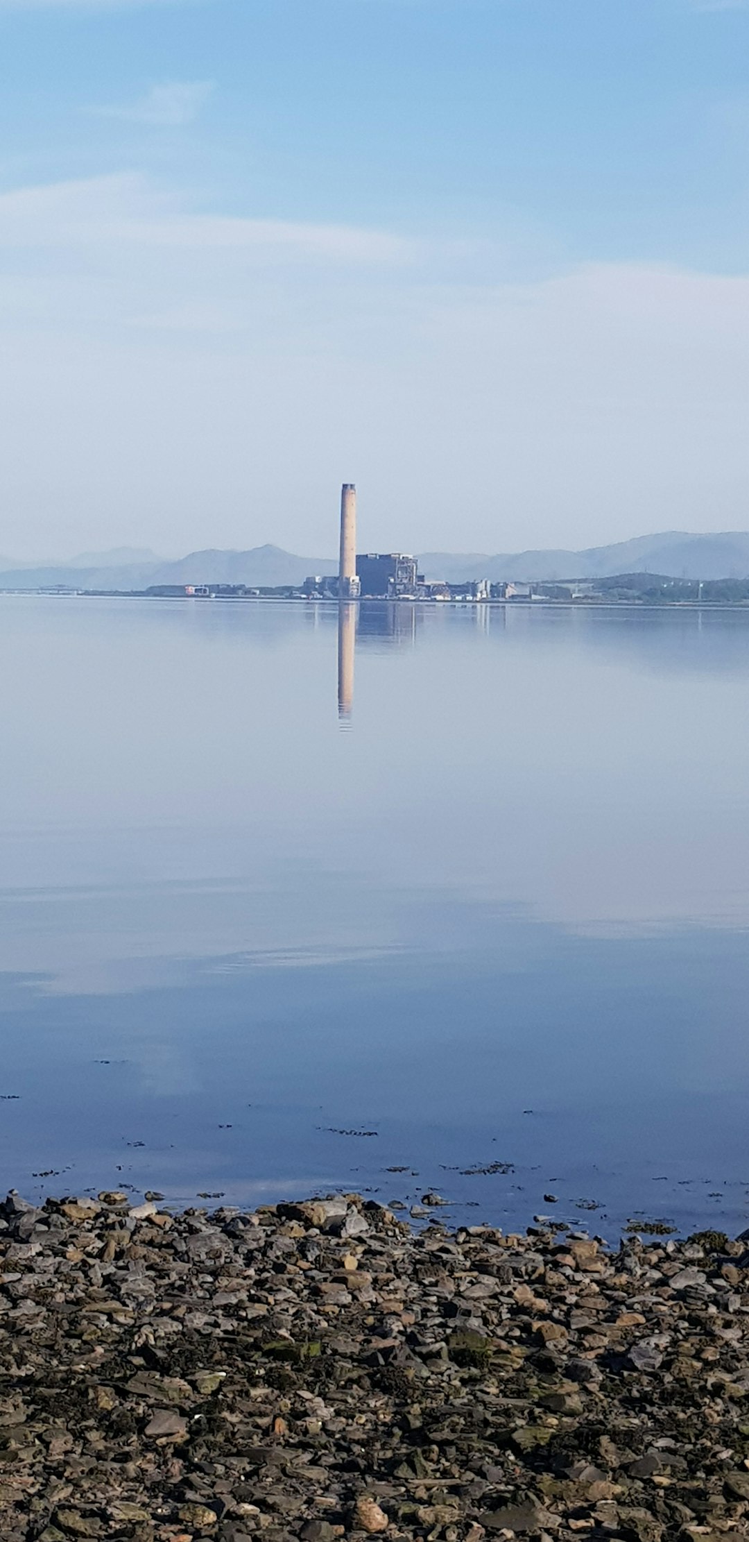 Kühlturm eines Kernkraftwerks spiegelt sich im See