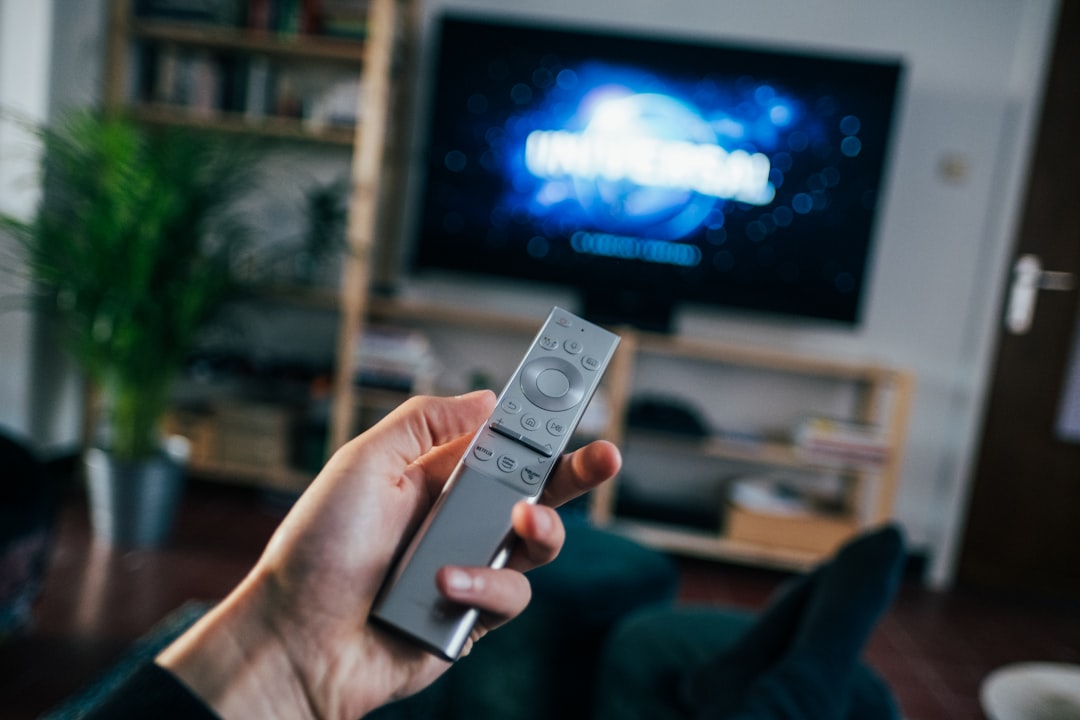 Mão com controle remoto apontando para Smart TV funcionando bem