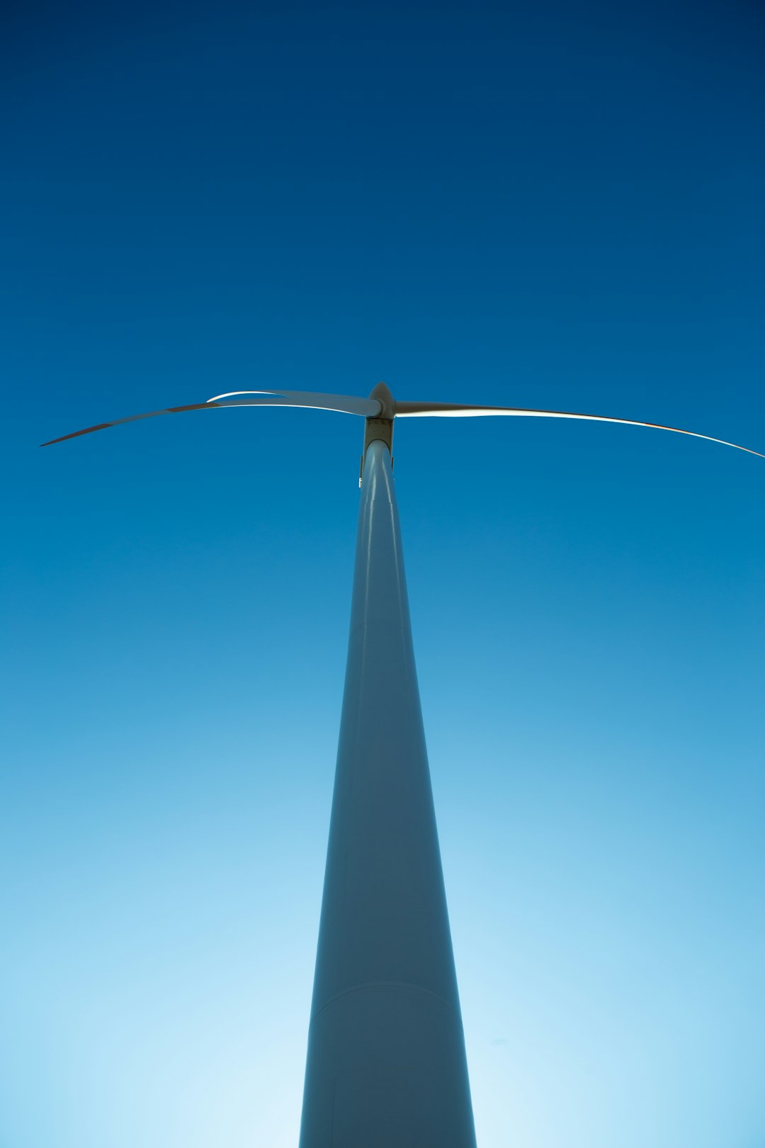 Windkraftanlage von unten gegen blauen Himmel fotografiert