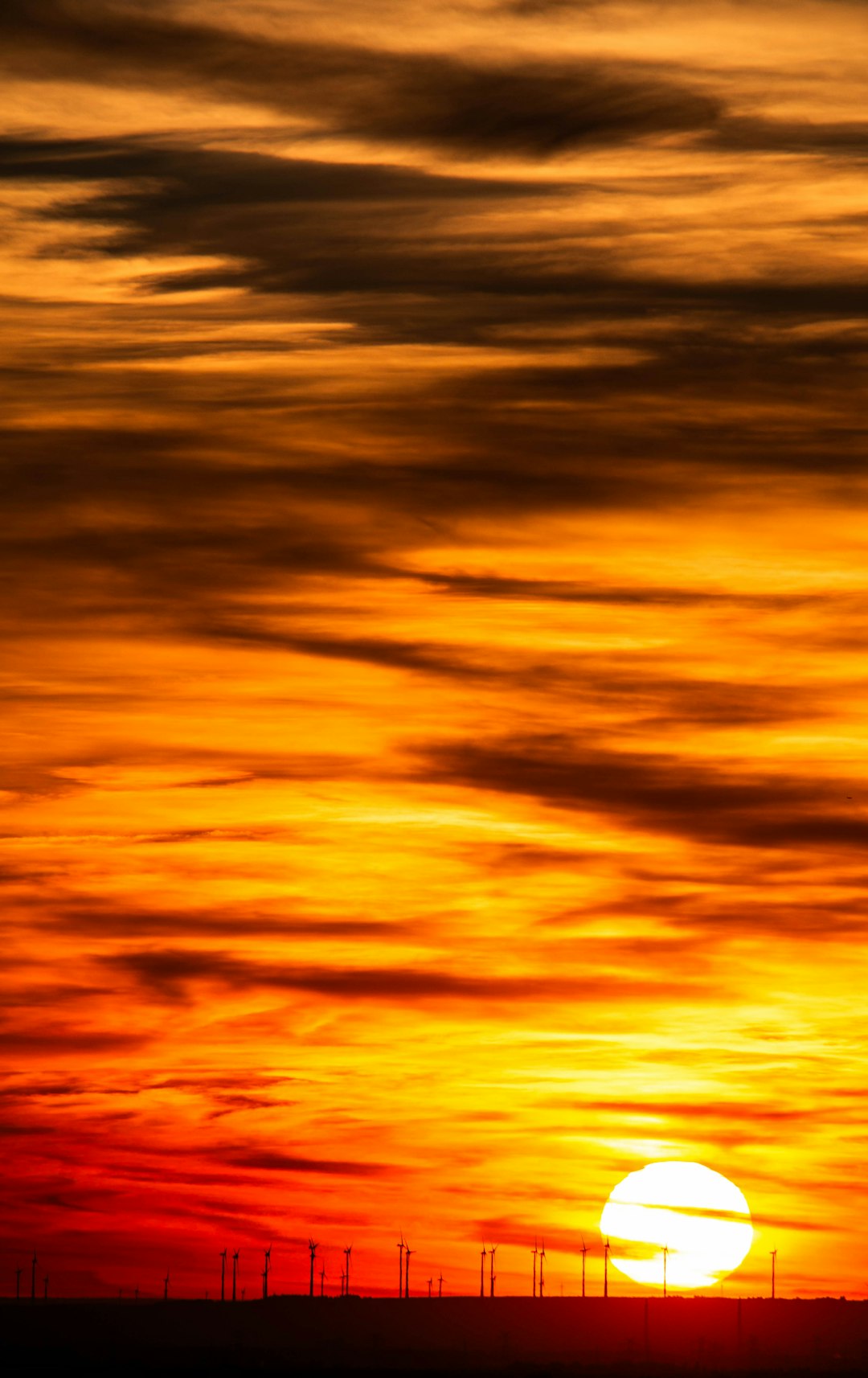 Sunset over wind turbines and thermal energy storage facility