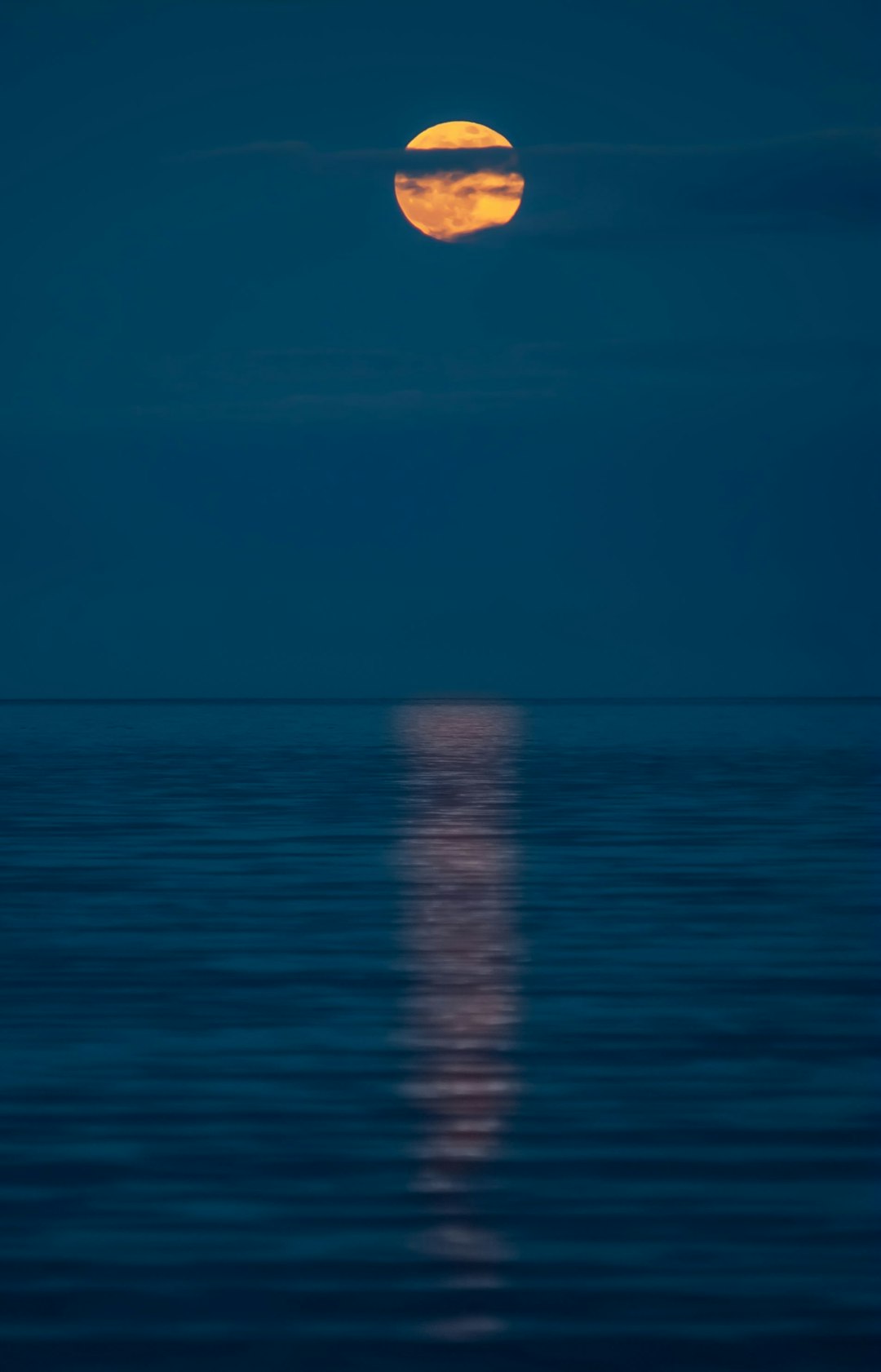 Full Moon rising over calm ocean at twilight
