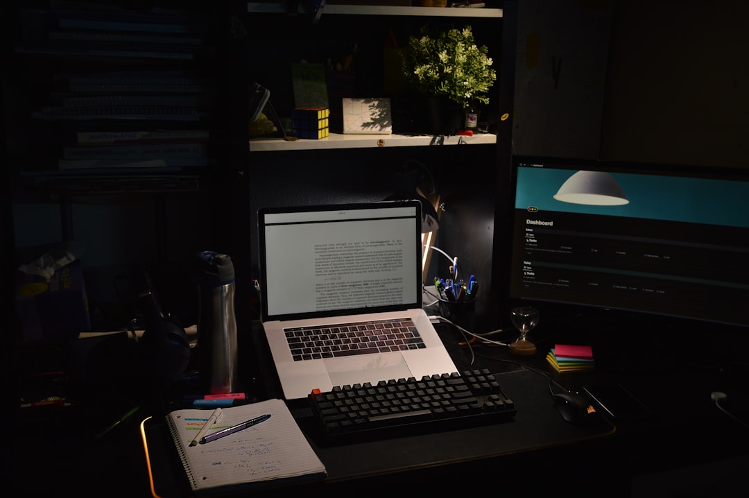 Manos escribiendo en teclado de portátil con iluminación dramática
