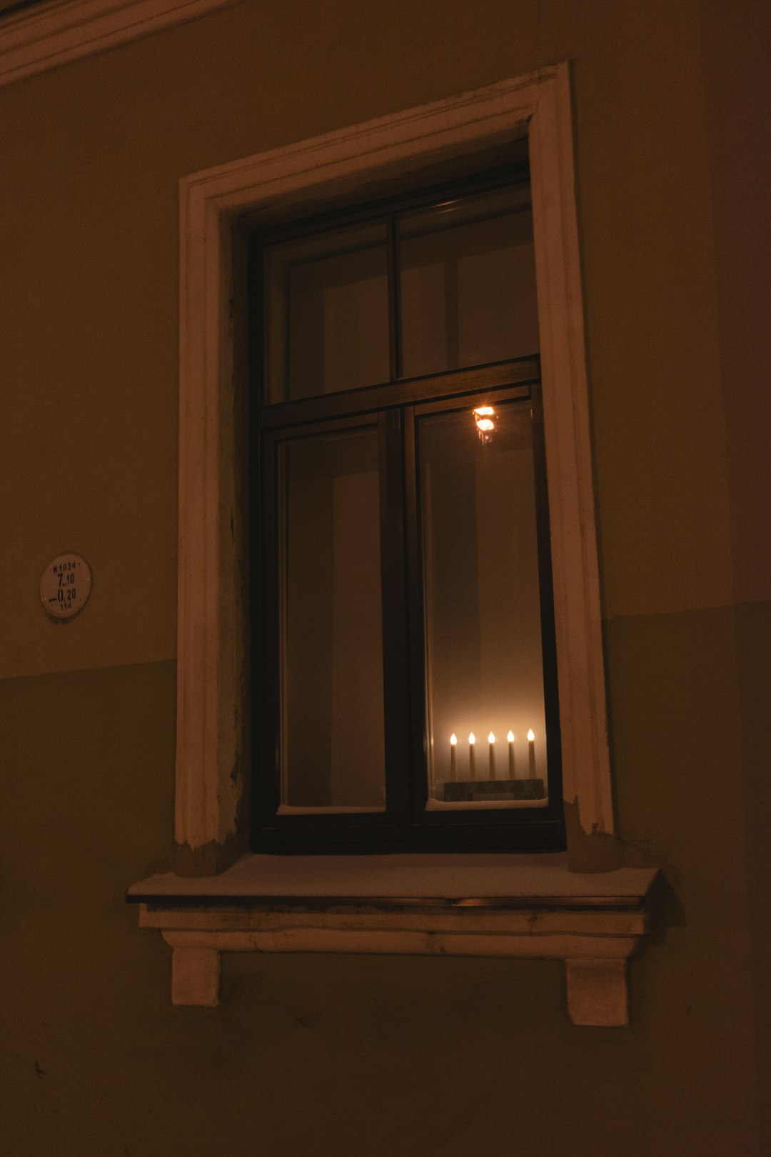 Candle and photograph beside a phone on a nighttime windowsill