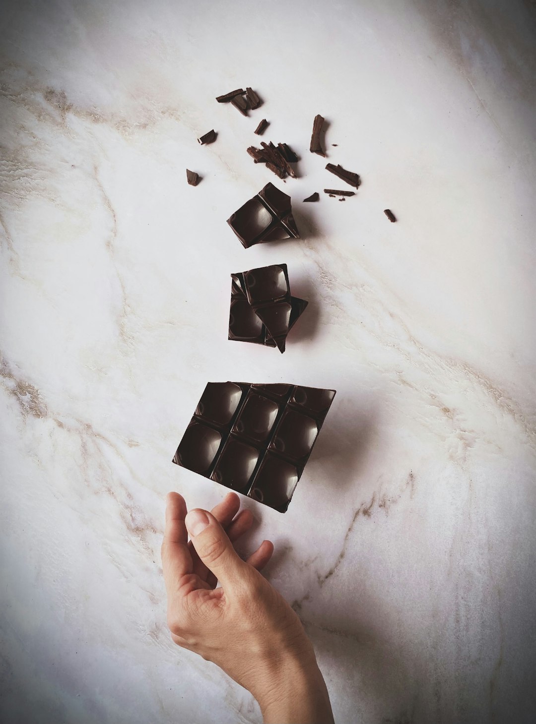 Carré de chocolat noir se brisant, grués de cacao et fragment de cabosse