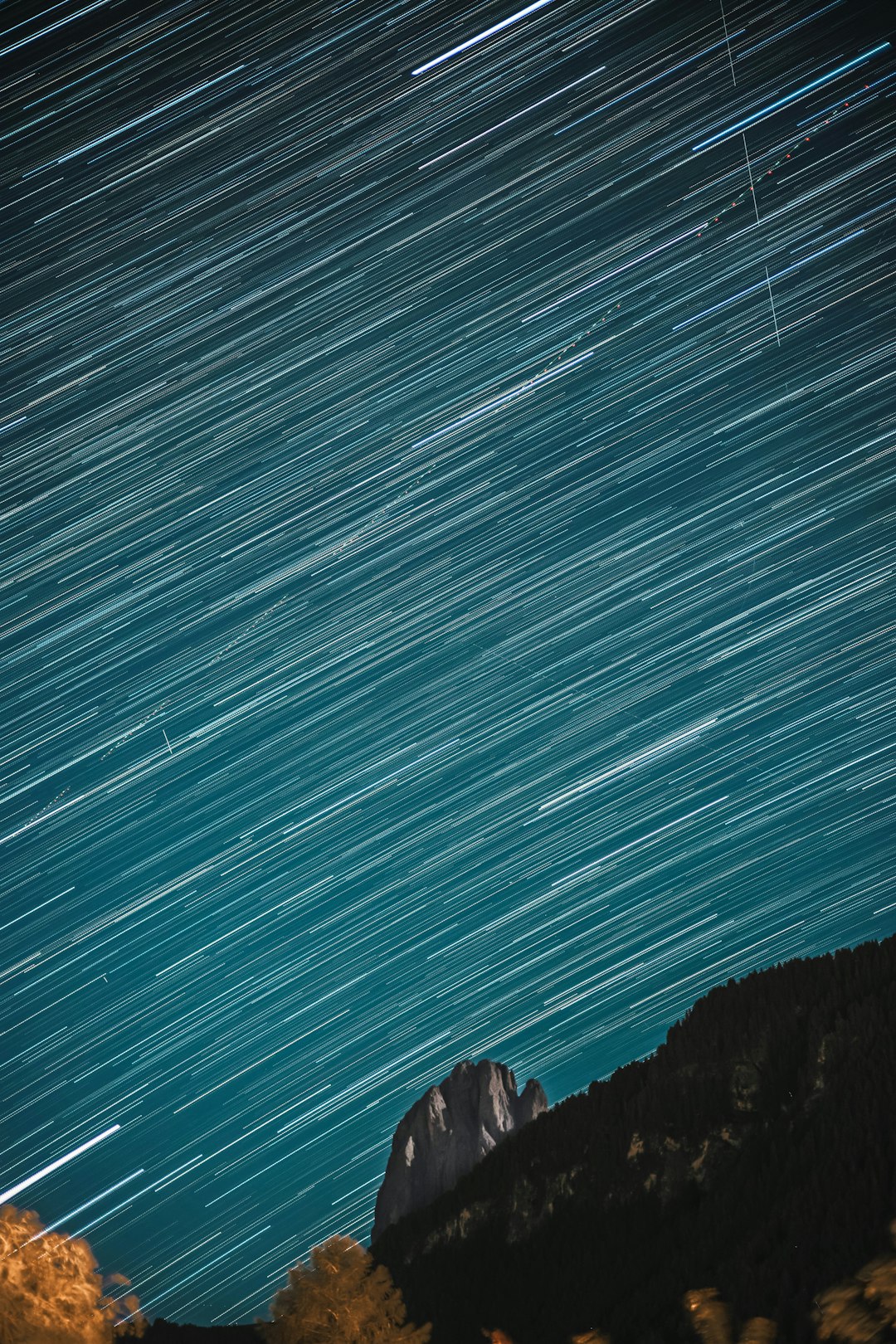 Meteor shower over mountain reflected in still lake