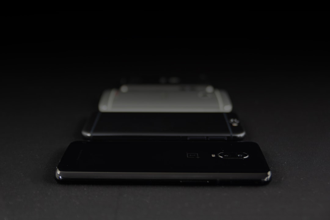 Two smartphones placed back-to-back on a dark surface