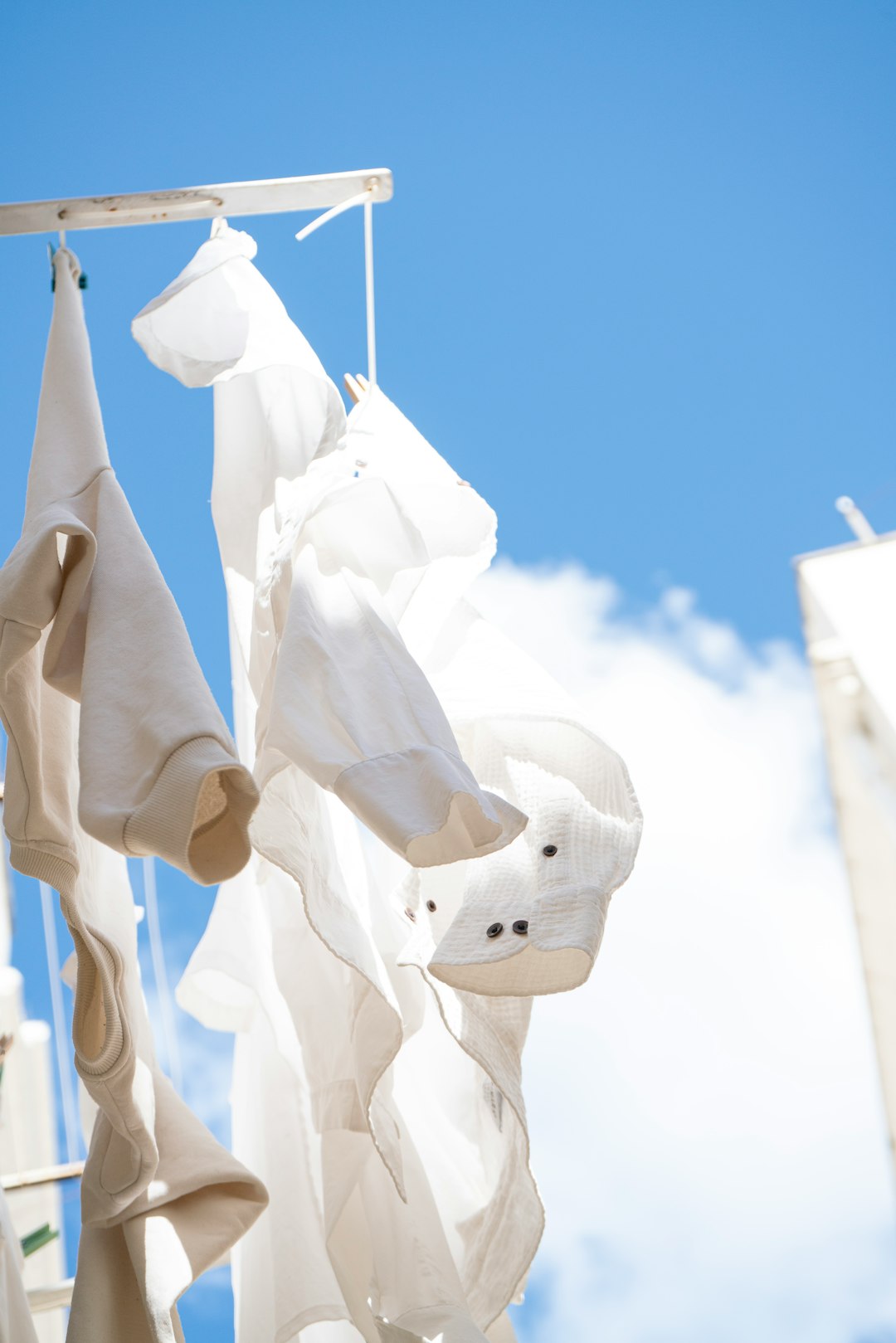 White linen shirt hanging outdoors against blue summer sky