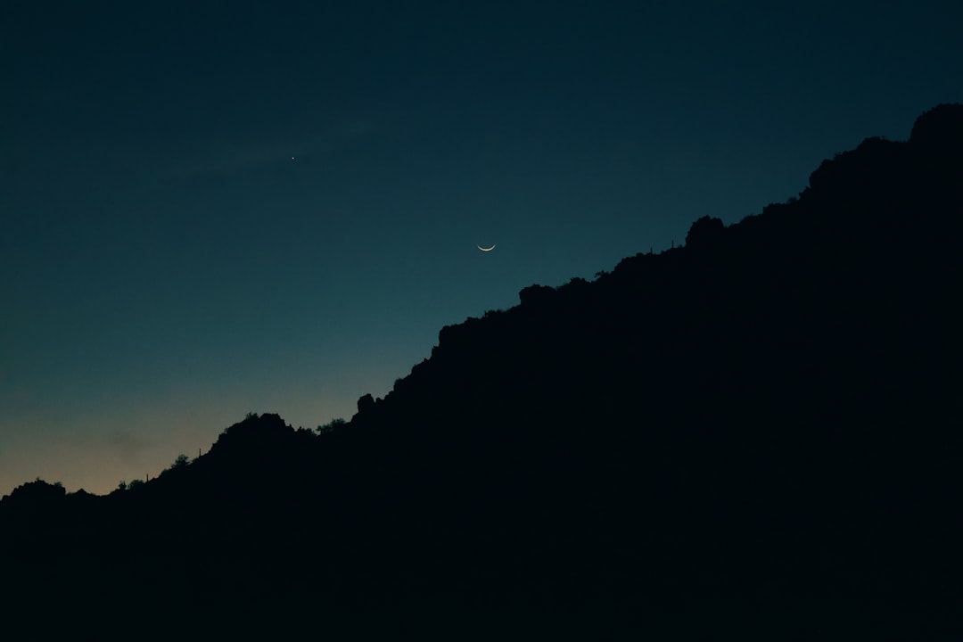 Crescent moon over mountain silhouette at twilight