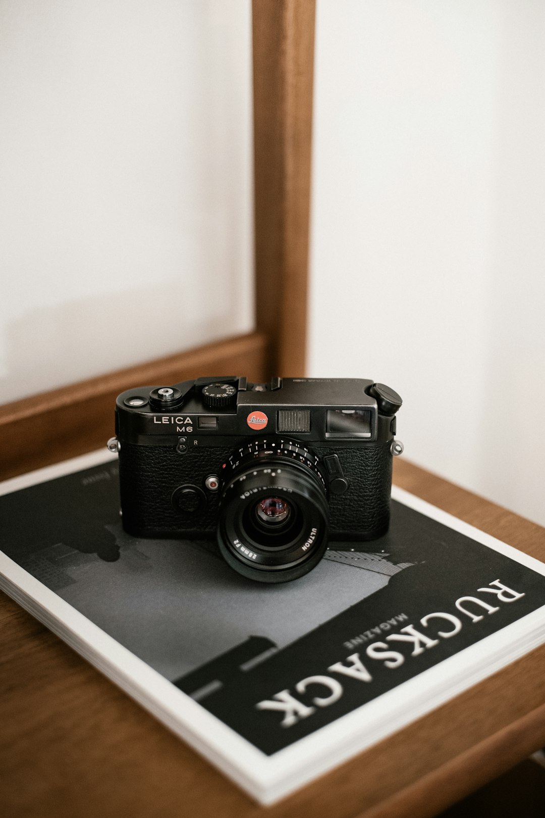 Mirrorless camera beside smartphone on wooden shelf