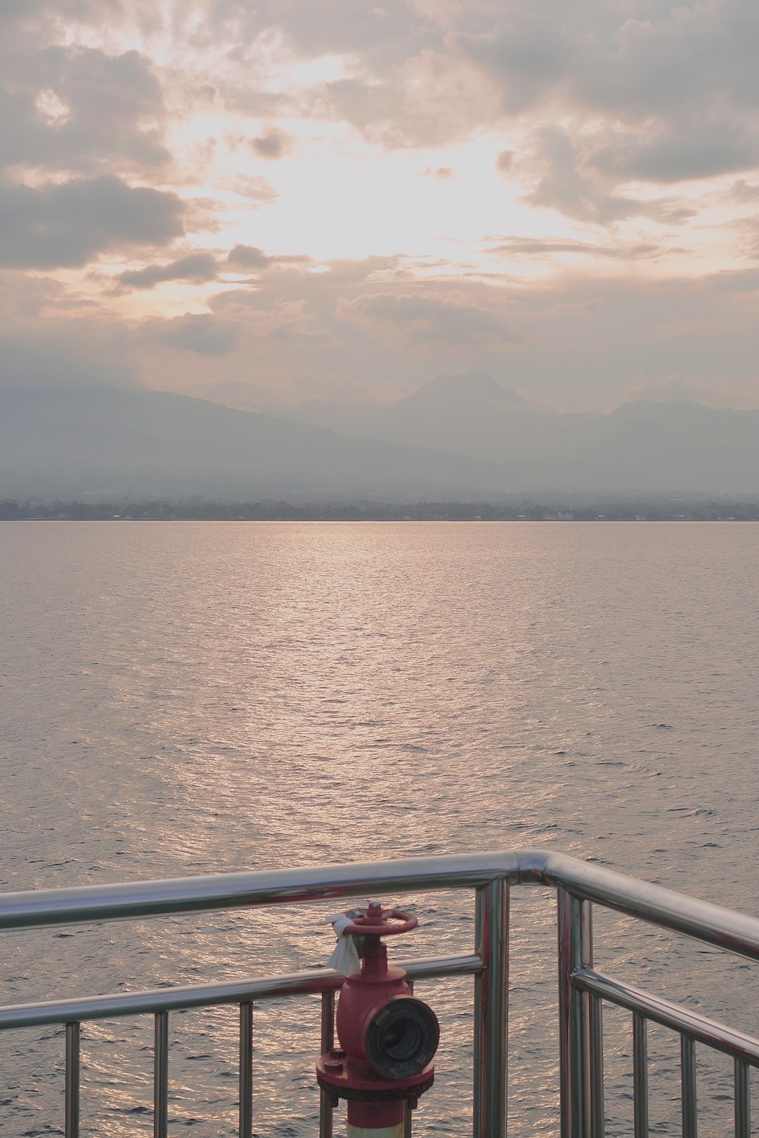 Person standing at ship deck looking at calm ocean horizon
